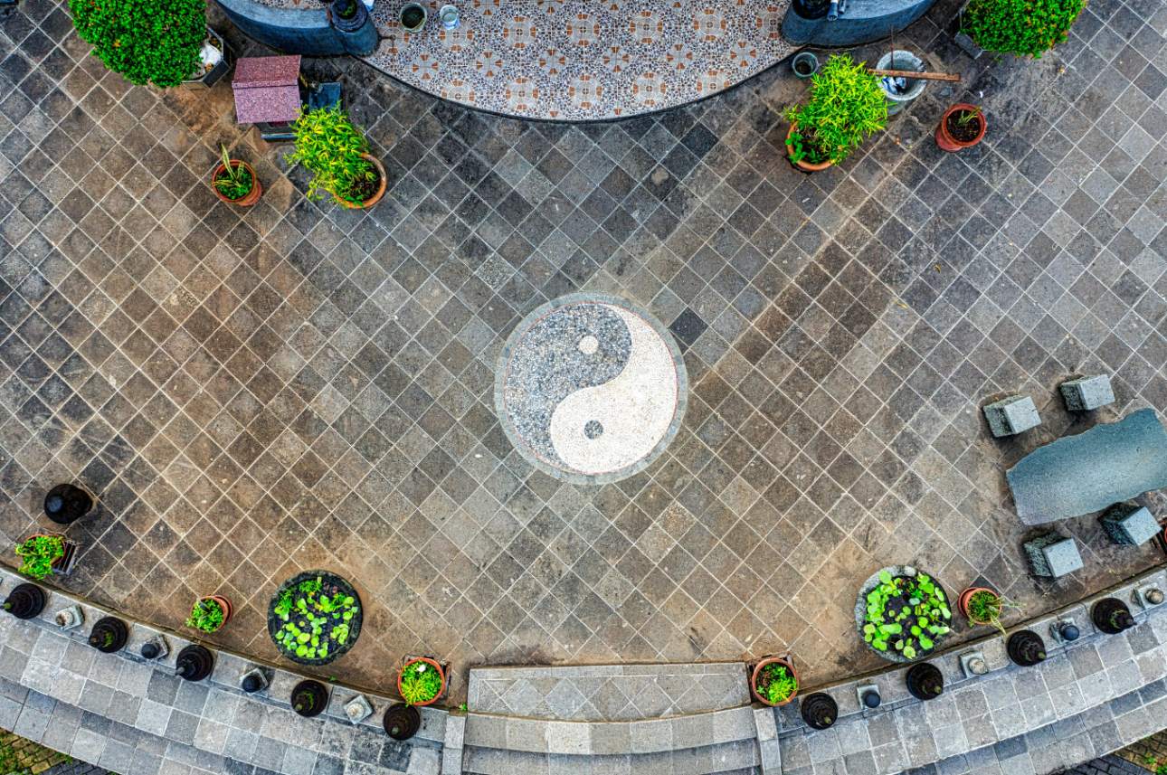 Yin-Yang-Mosaik auf gepflastertem Platz mit Pflanzen in Töpfen, aus der Vogelperspektive