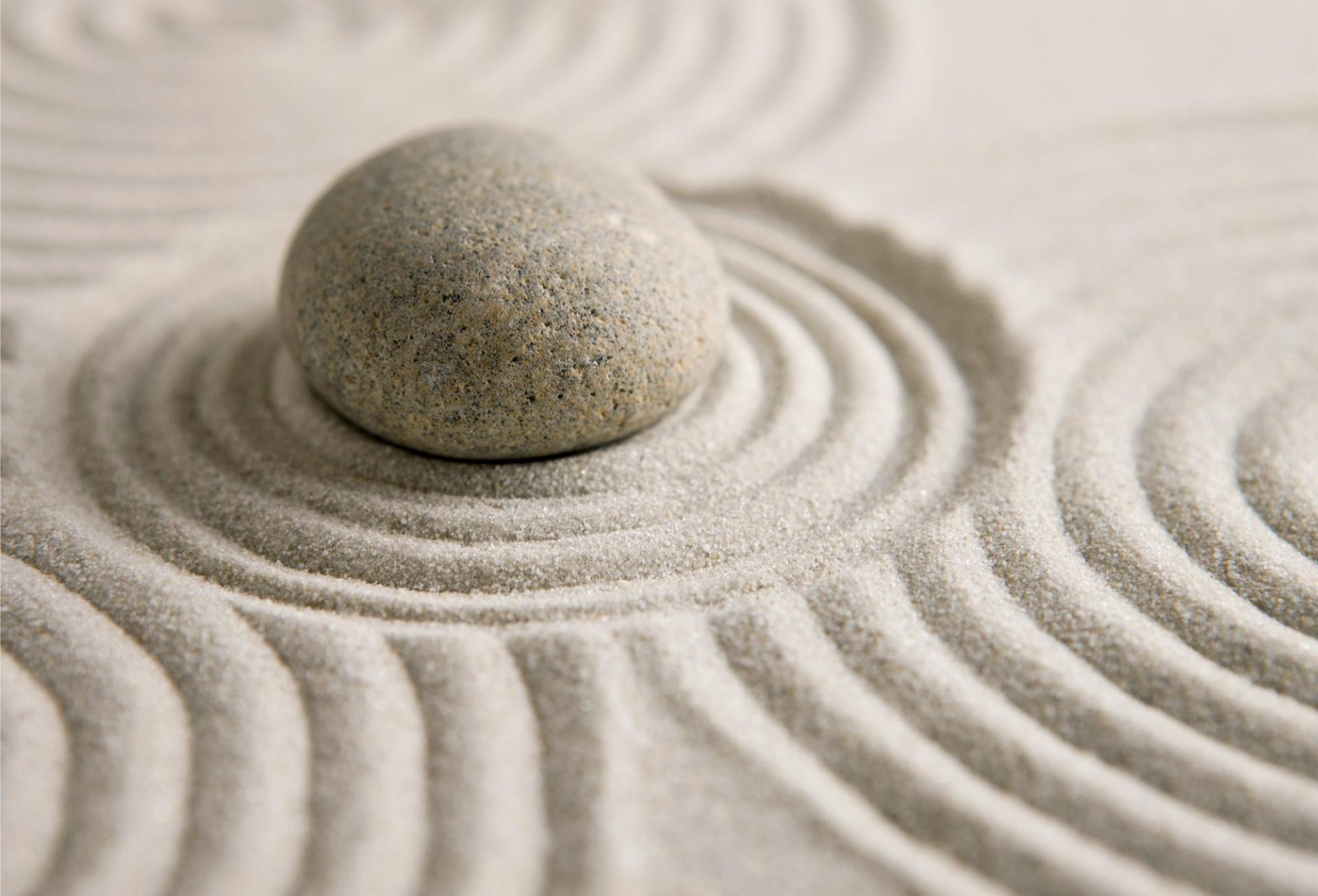 Zen-Garten mit Linien im Sand und gestapelten schwarzen sowie einem hellen Stein